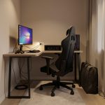 Petit coin gaming aménagé dans un salon moderne, avec bureau compact, fauteuil ergonomique, écran, éclairage chaleureux et rangement optimisé.